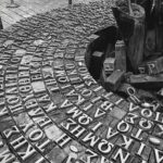 Black and white photo of an abstract sculpture with letters in Chipre's urban setting. Unique design.